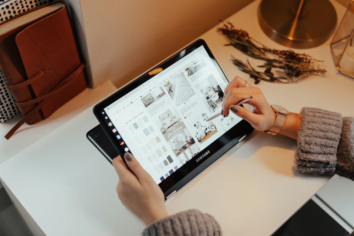Manos usando una tablet sobre un escritorio blanco con decoración inspiradora.