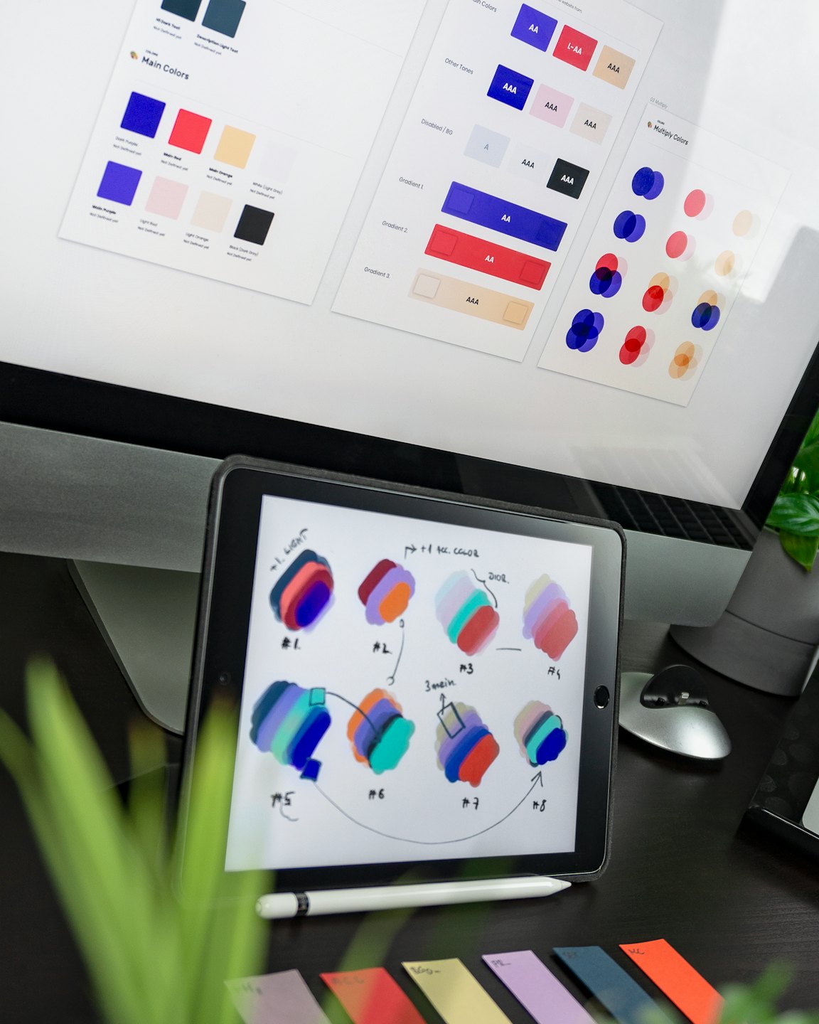 Monitor de computadora y tableta mostrando trabajo de diseño y muestras de color.